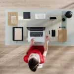 top view, a woman sitting at tidy desk and working on her laptop